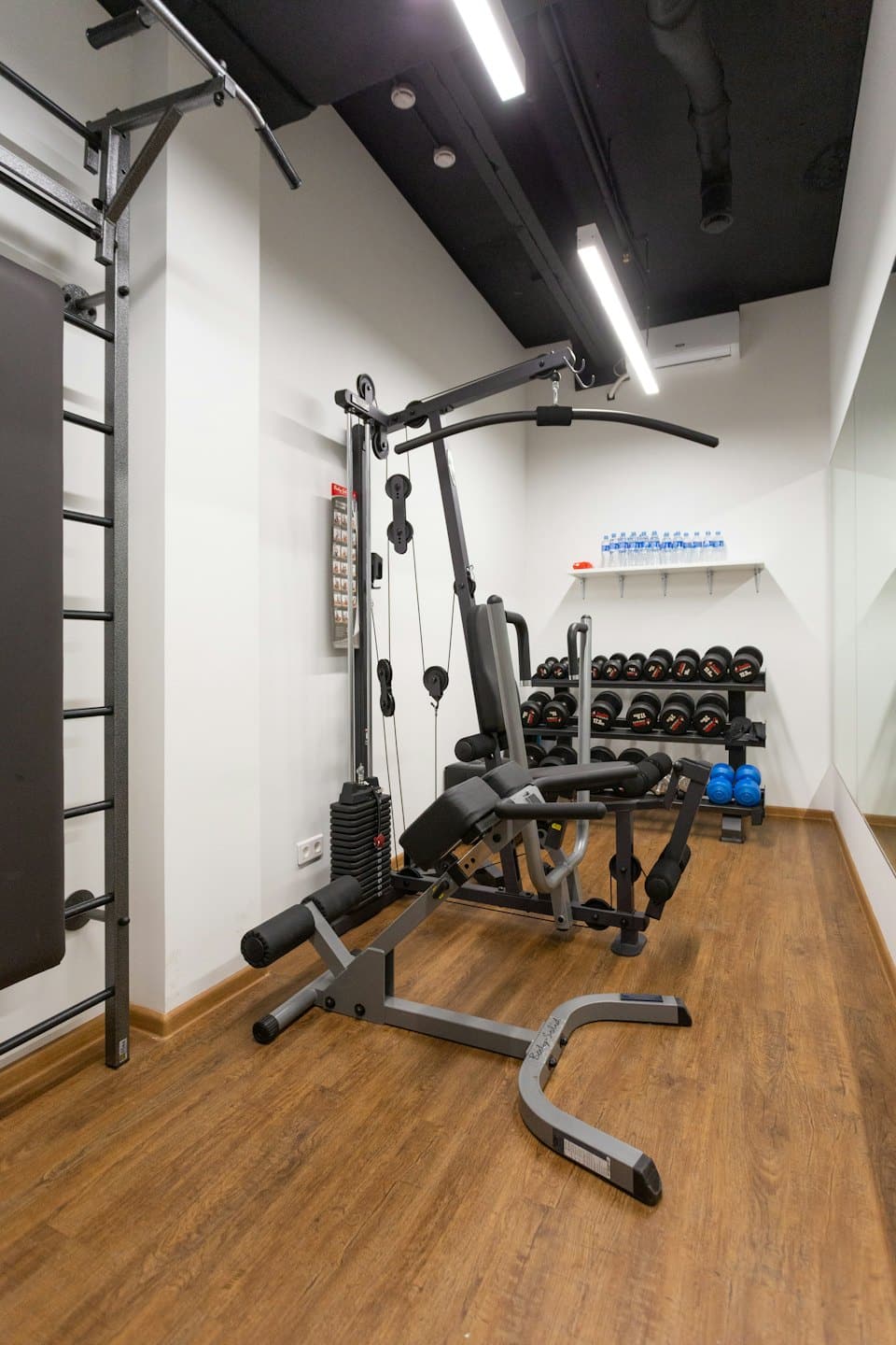 Empty private gym with multi-gym, dumbbells, and kettlebells.