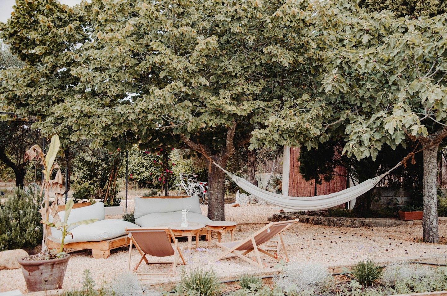 A white hammock and outdoor furniture arranged on a gravel patio.