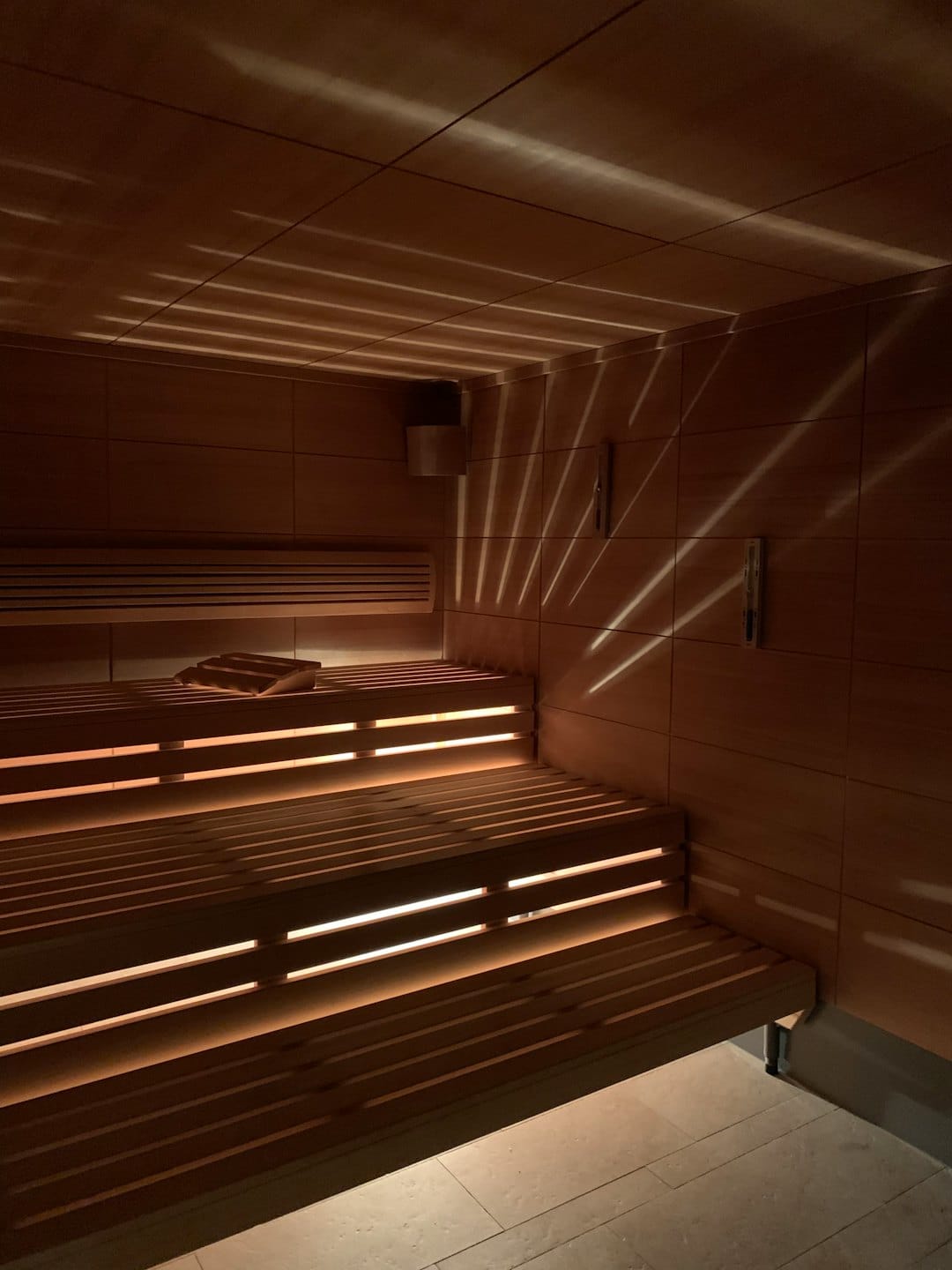 Empty wooden sauna room with slatted benches and glowing lights.
